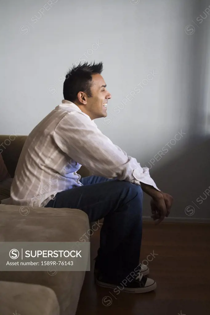 Smiling mixed race man sitting on sofa