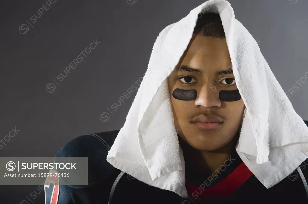 Mixed race football player with towel on head