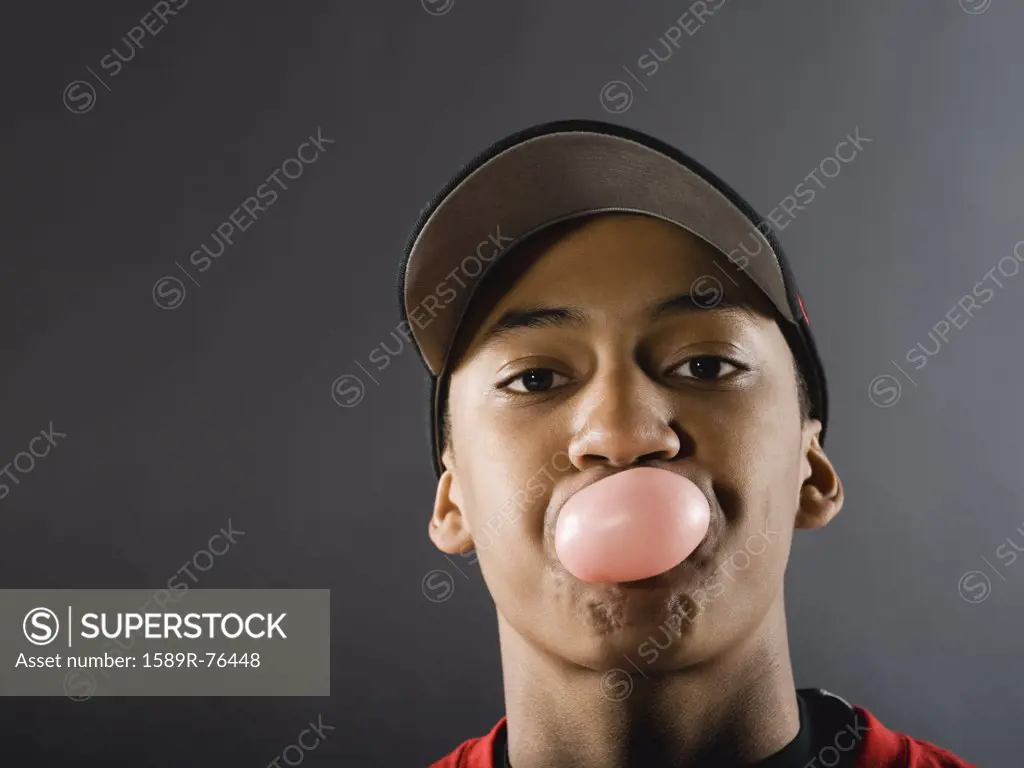 Mixed race baseball player blowing bubble with gum