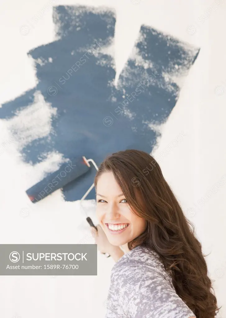 Mixed race woman painting wall