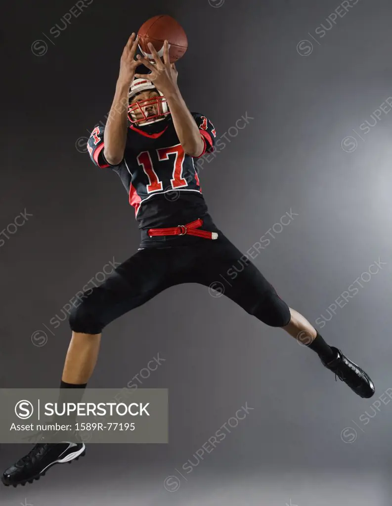Mixed race football player catching football