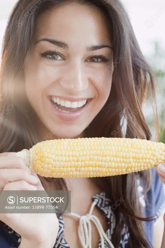 Hispanic woman eating ear of corn