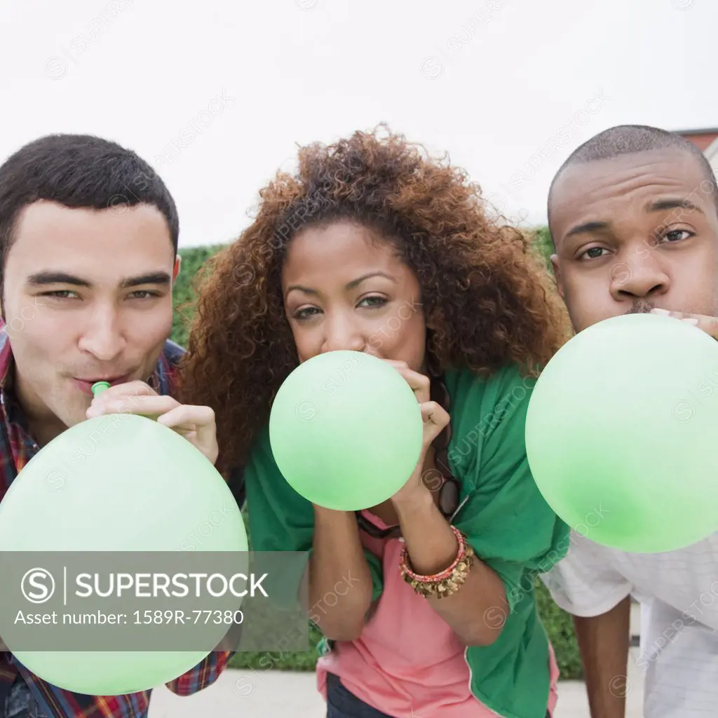 Friends blowing up green balloons