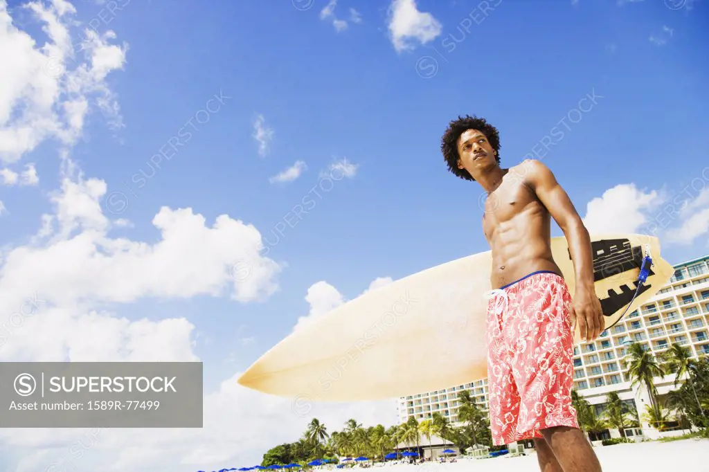 African man holding surfboard on beach
