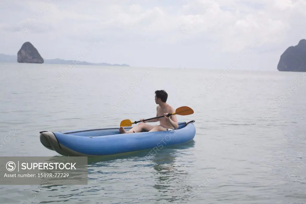Chinese man paddling boat in ocean