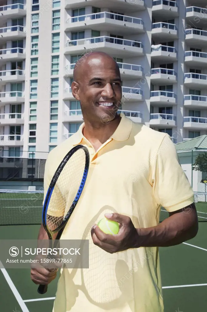 African man holding tennis ball and racket