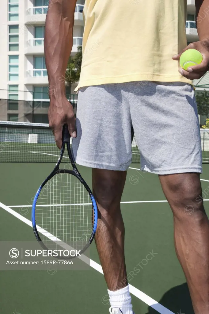 African man holding tennis ball and racket