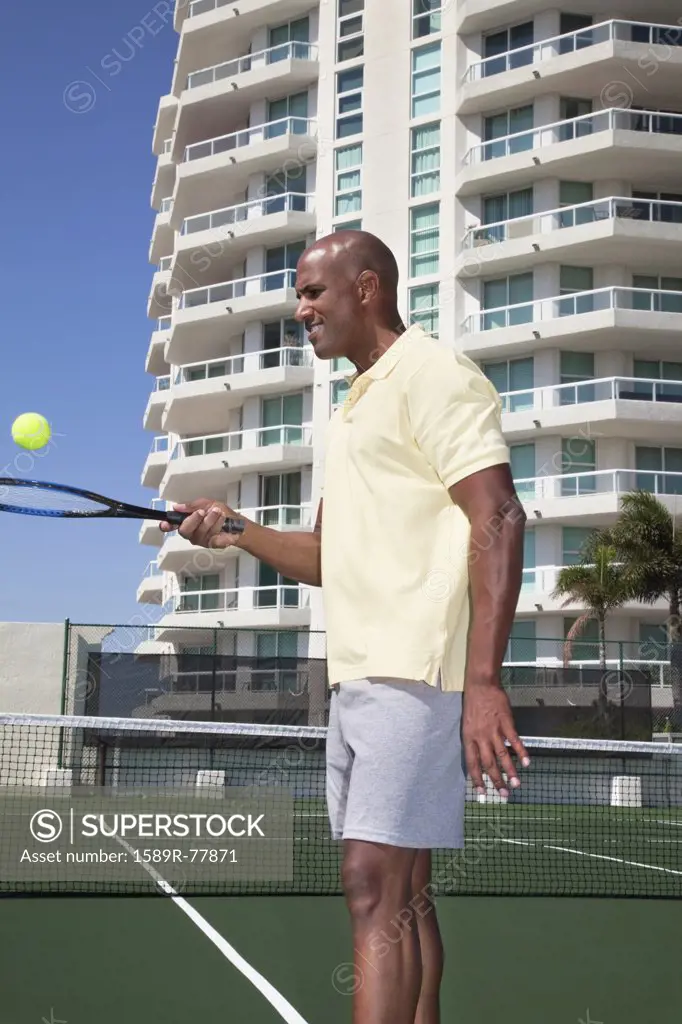 African man balancing tennis ball on racket