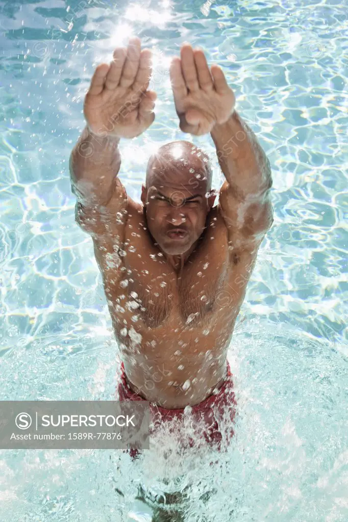African man jumping out of swimming pool