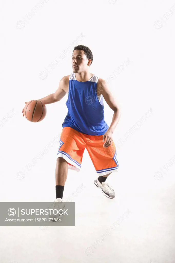 Mixed race basketball player dribbling ball