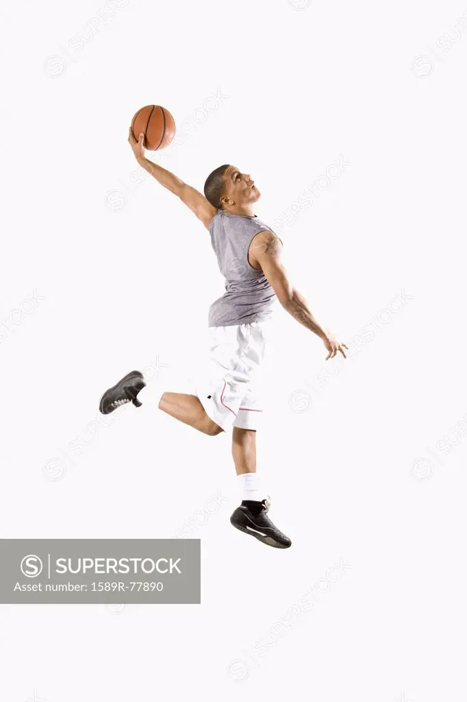 Mixed race basketball player dunking ball