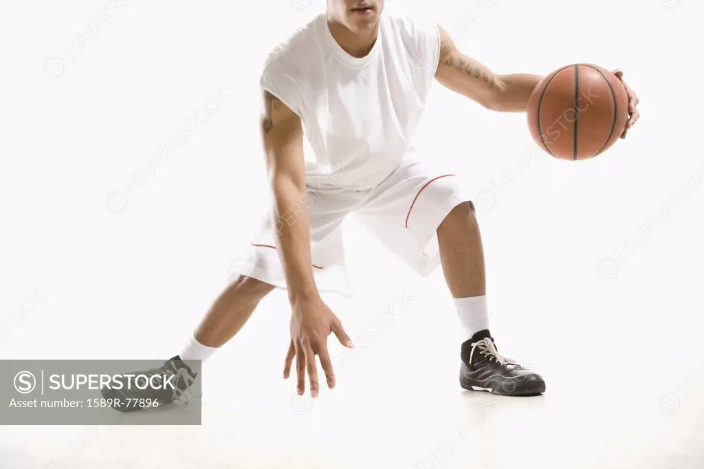 Mixed race basketball player dribbling ball