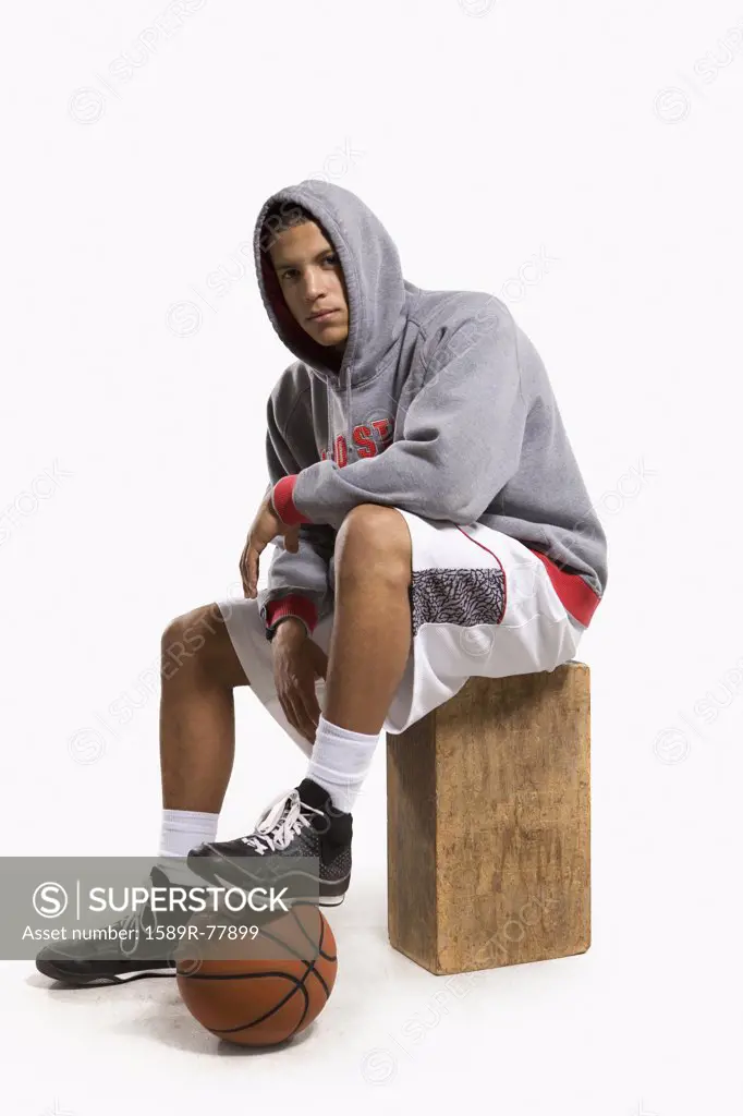 Mixed race basketball player with foot on ball