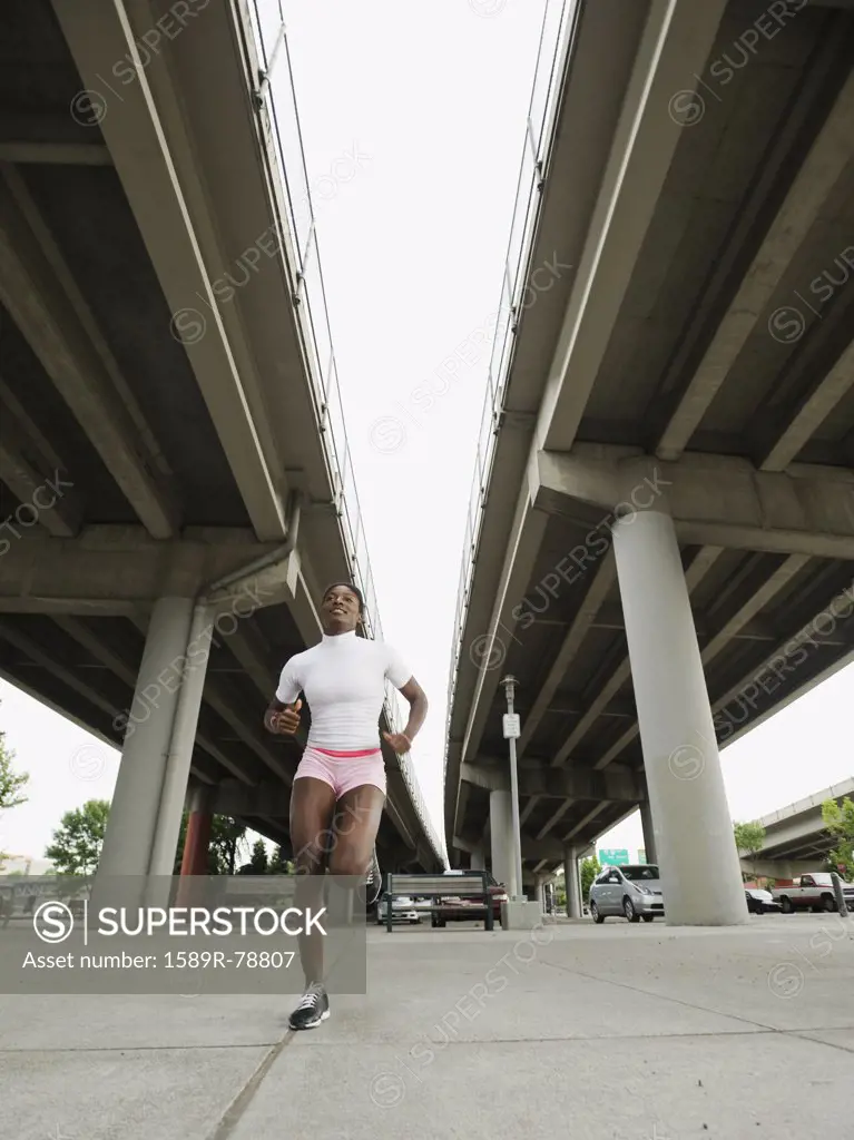 African woman running under freeway overpass