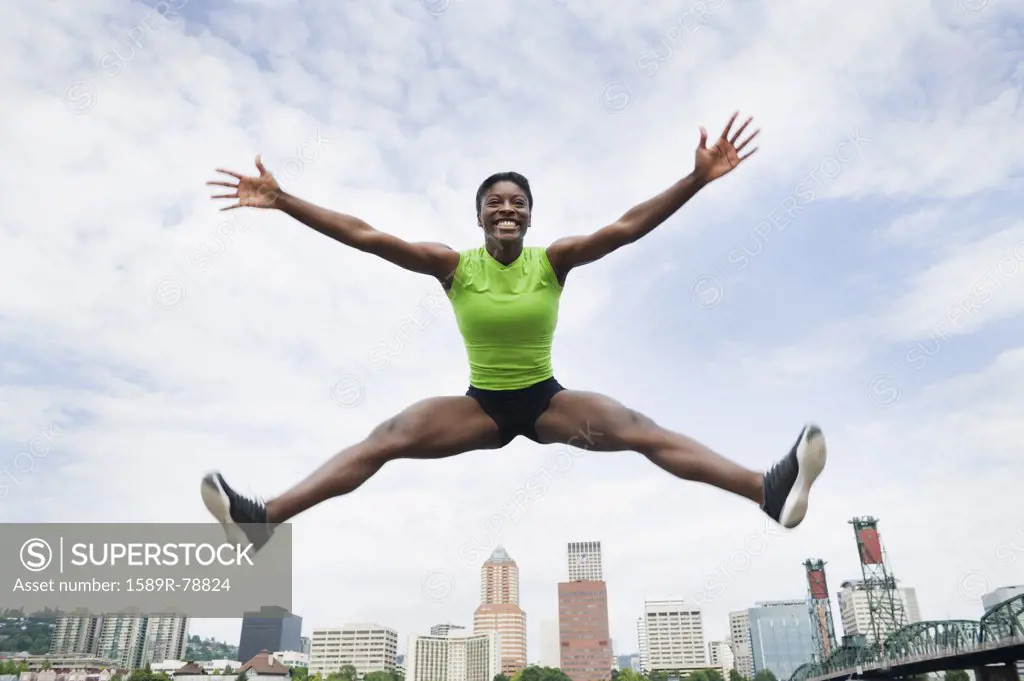 African woman jumping with city in background