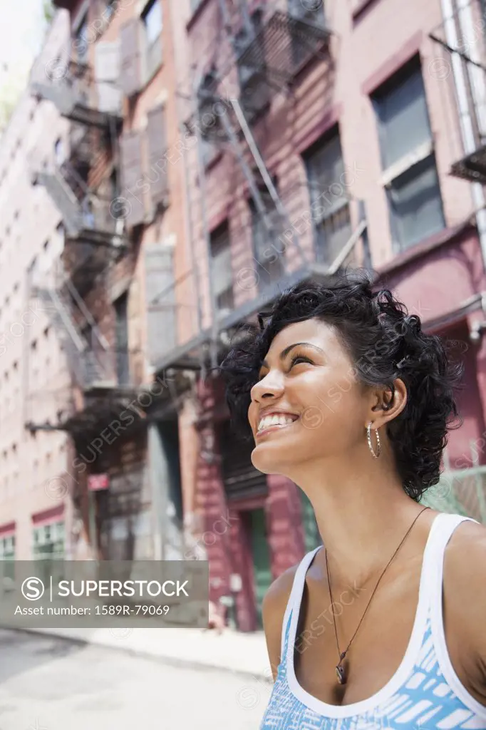 Mixed race woman looking up on urban street