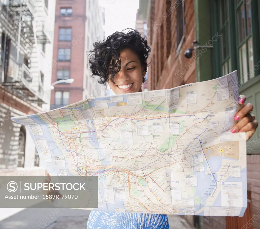 Mixed race woman holding map on urban street