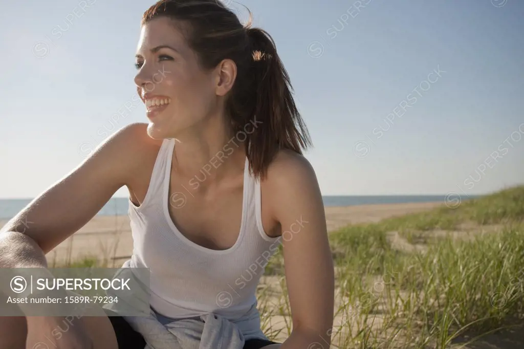 Mixed race woman in sportswear smiling on beach