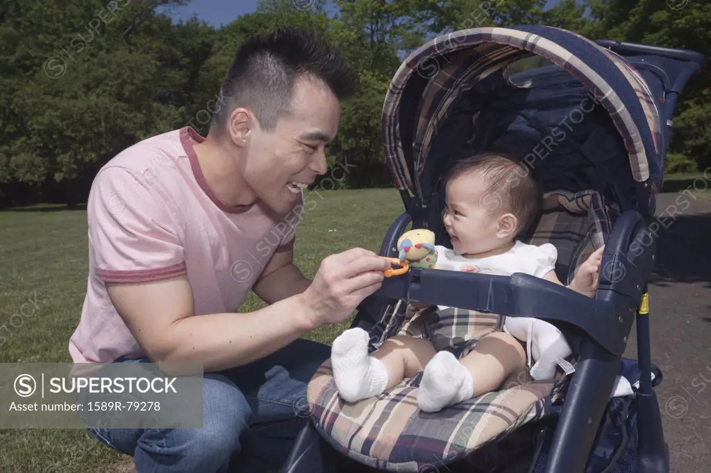 Chinese father and baby in stroller at park