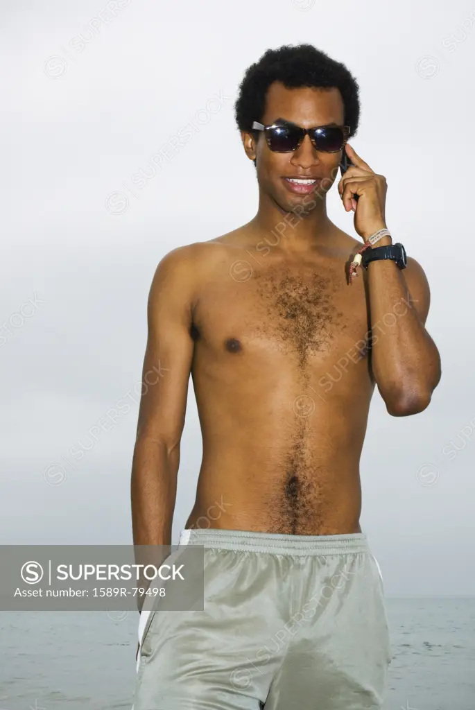 Mixed race man talking on cell phone at ocean