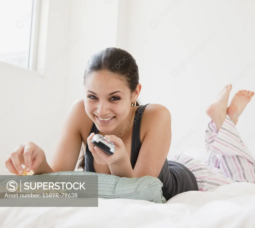 Mixed race woman eating popcorn and watching television