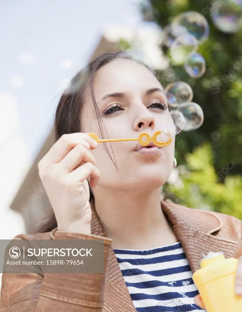 Mixed race woman blowing bubbles
