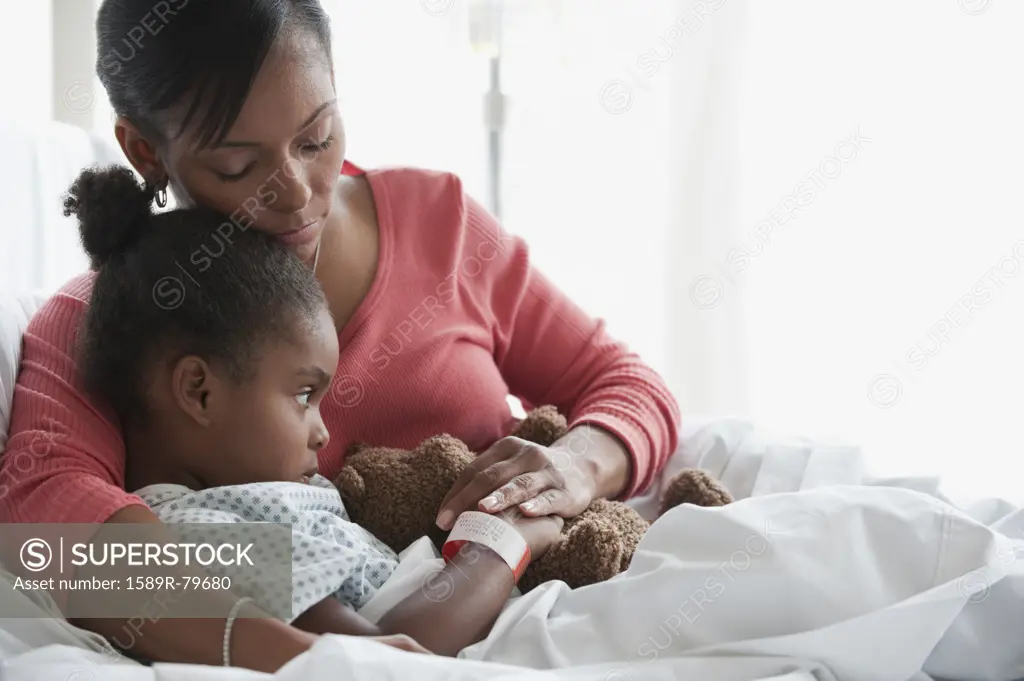 Mixed race mother comforting child in hospital bed