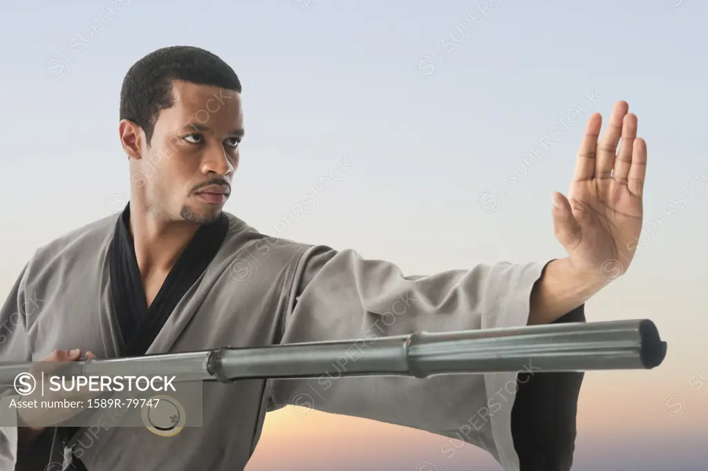 Mixed race martial artist holding stick
