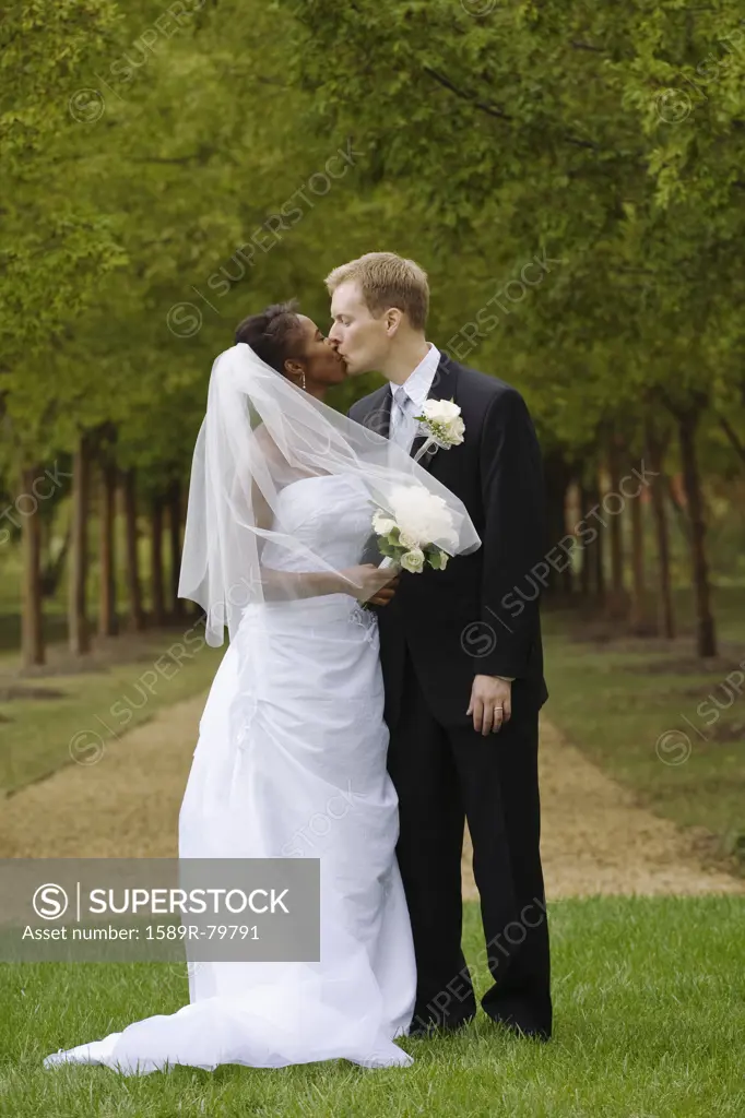 Bride and groom kissing in grass