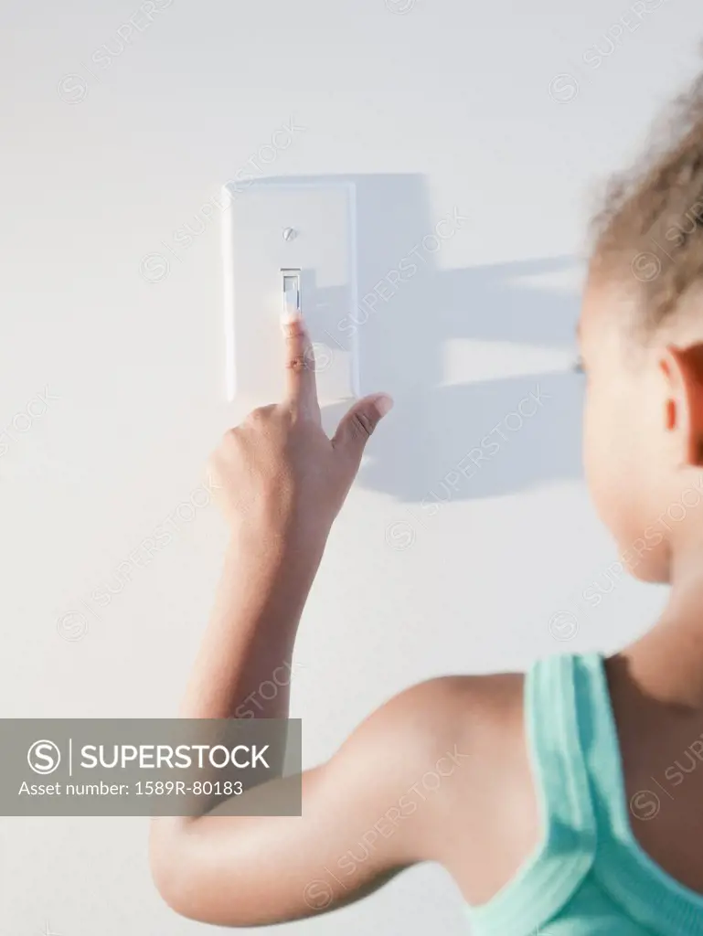 Mixed race girl turning off light
