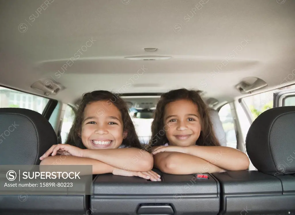 Hispanic sisters in back seat of car
