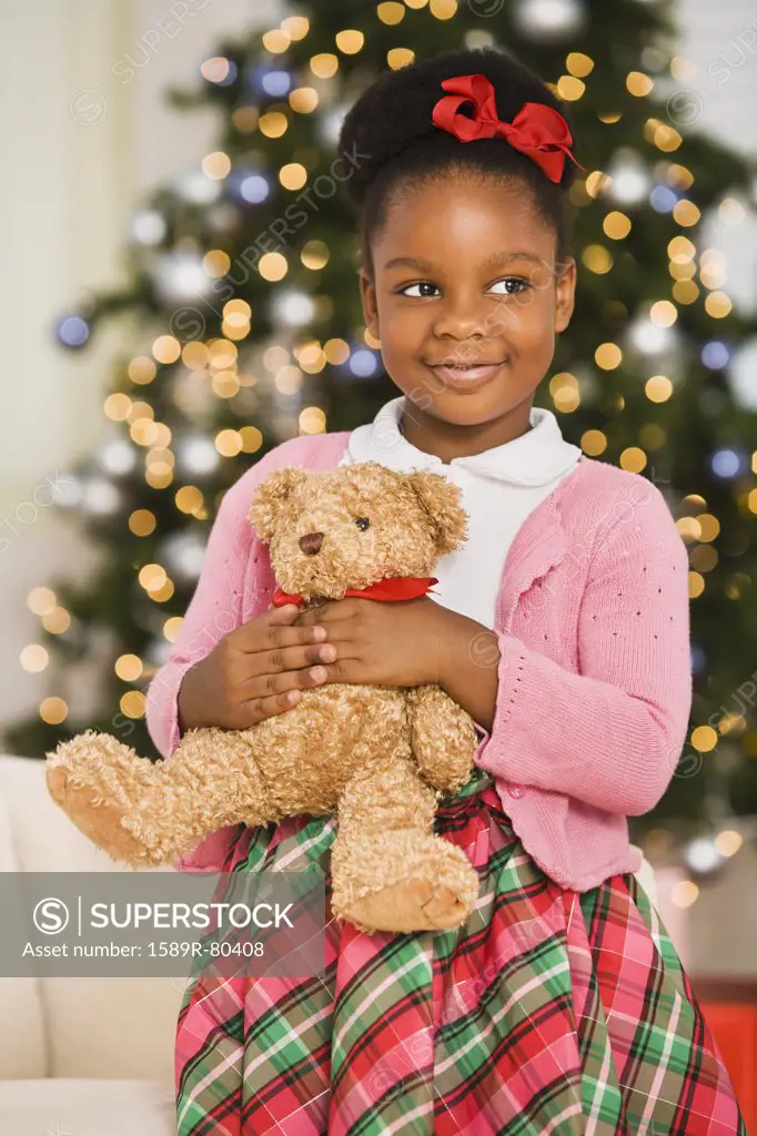 African girl holding teddy bear at Christmas
