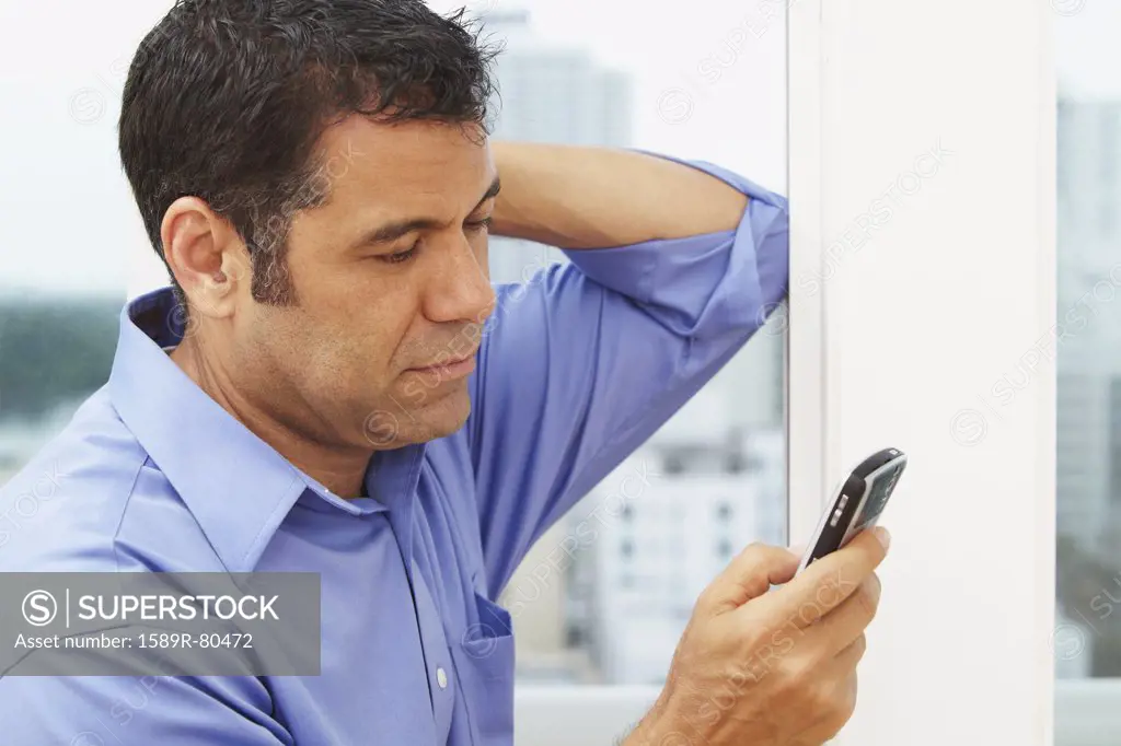 Hispanic businessman text messaging on cell phone