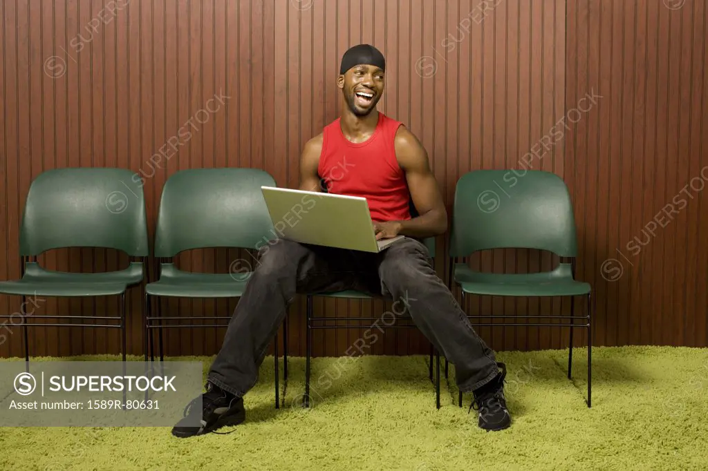 African man using laptop and laughing
