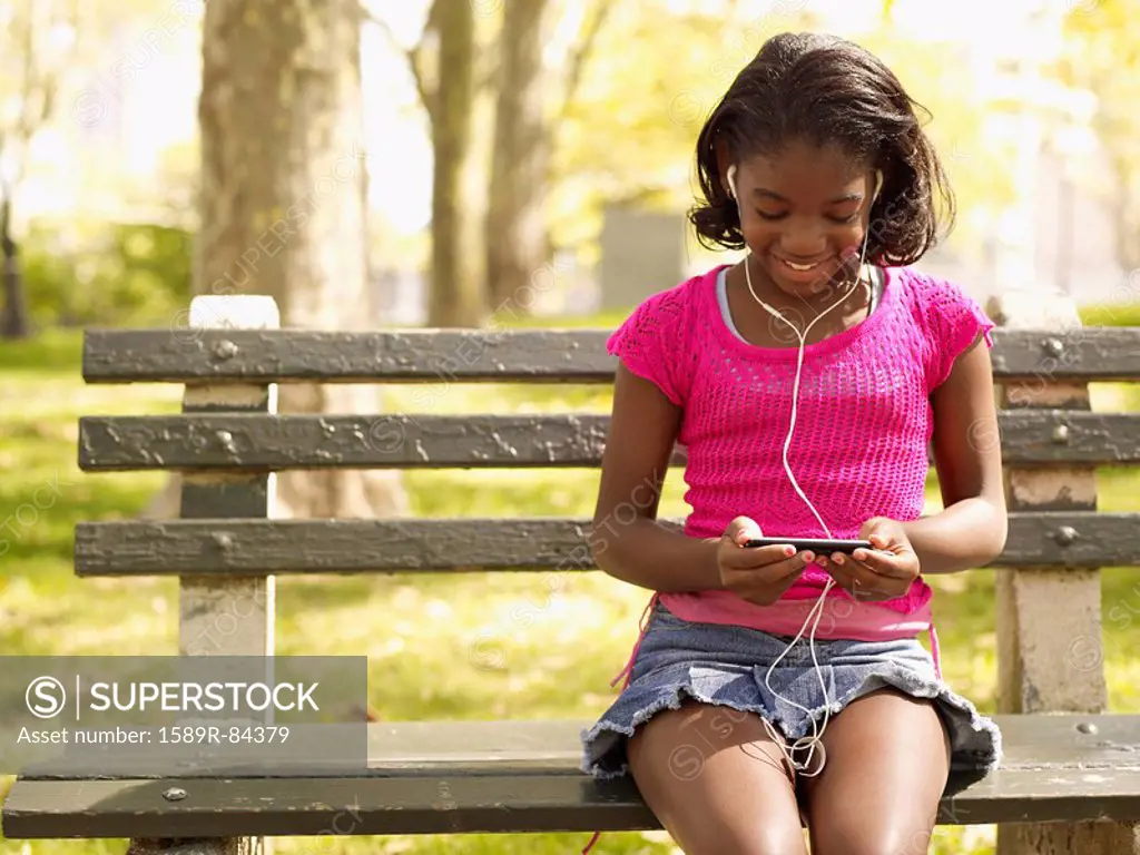 African girl listening to mp3 player in park