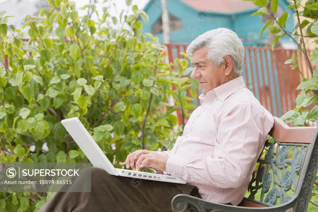 Senior Hispanic man typing on laptop