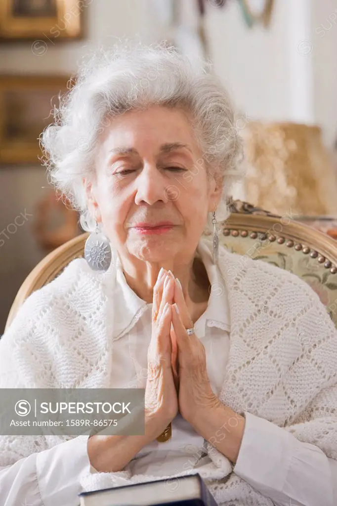 Senior Hispanic woman praying