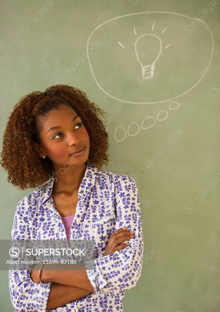 Mixed race woman standing next to thought bubble on blackboard