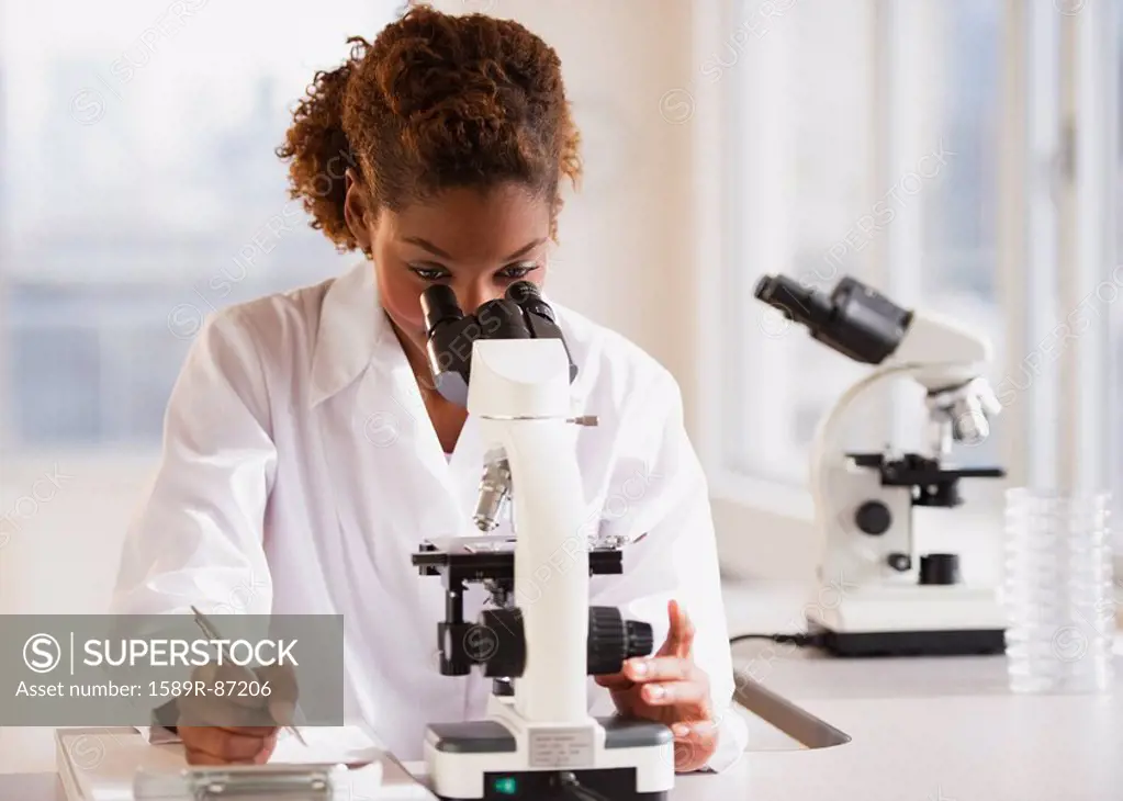 Mixed race scientist peering into microscope