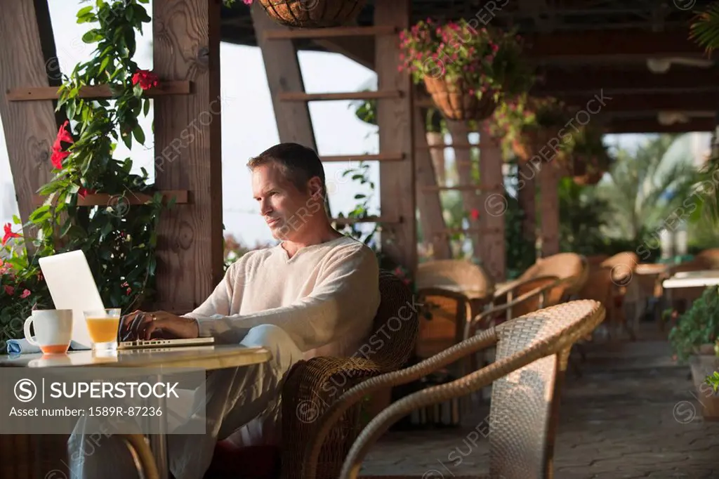 Caucasian man typing on laptop in restaurant