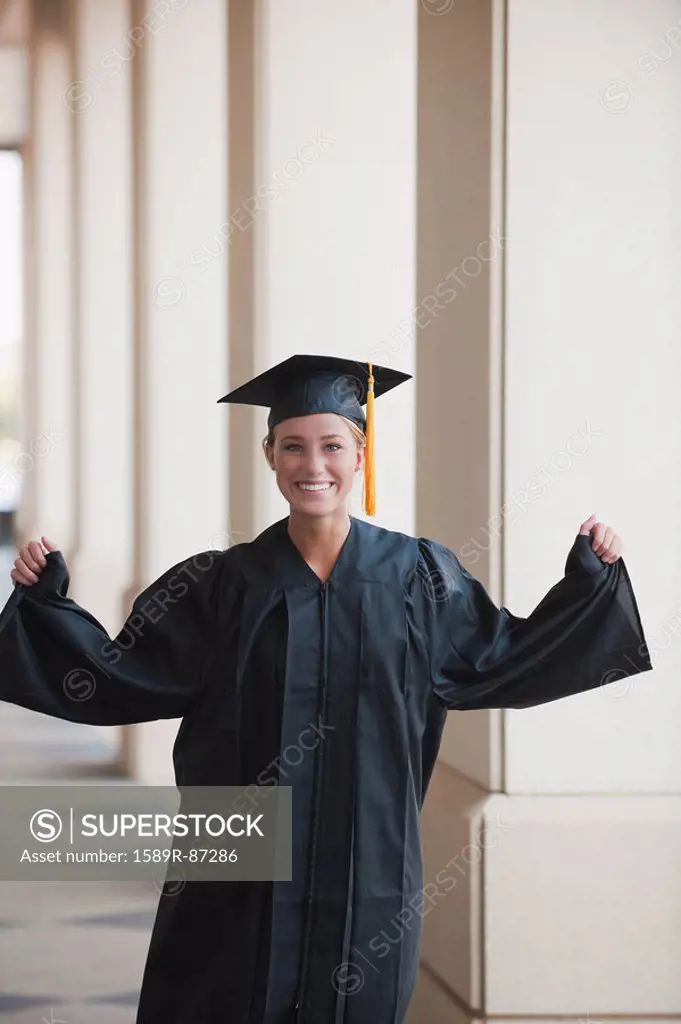 Caucasian graduate cheering in cap and gown