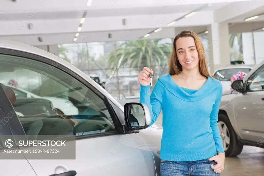 Hispanic woman holding keys to new car