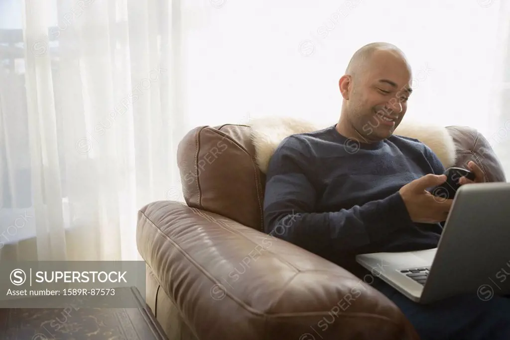 Mixed race man with laptop using cell phone