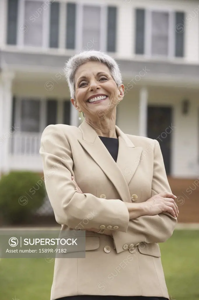 Businesswoman standing in front of house