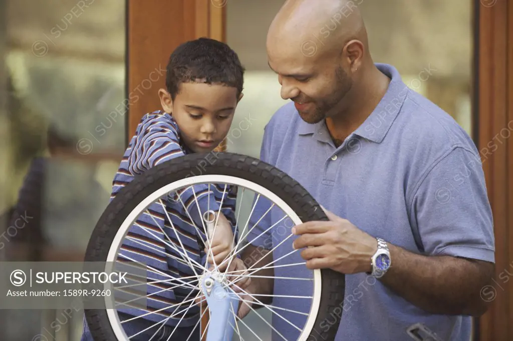 Father helping son fix bike