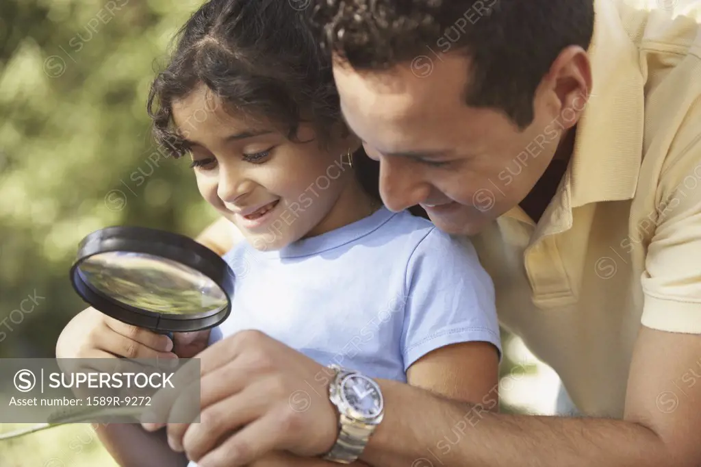 Father and daughter looking at caterpillar through magnifying glass
