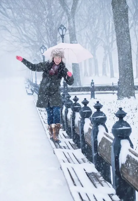 Asian woman walking on benches in snowy Central Park, New York City, New York, United States