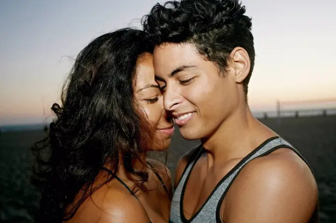 Hispanic couple hugging on beach