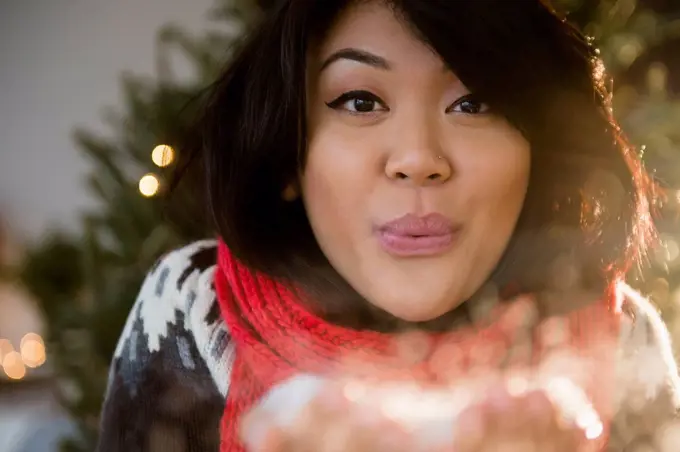 Pacific Islander woman blowing snow at Christmas