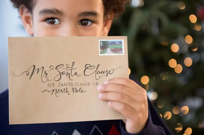 Mixed race boy holding letter to Santa for Christmas